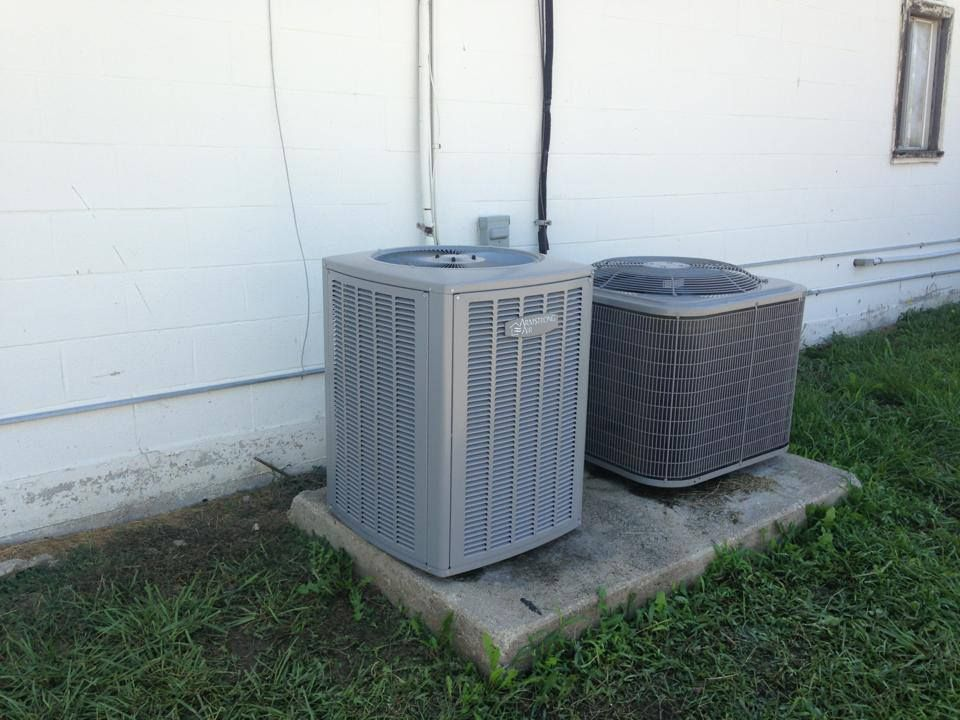 Outdoor HVAC condenser unit on gravel beside a building