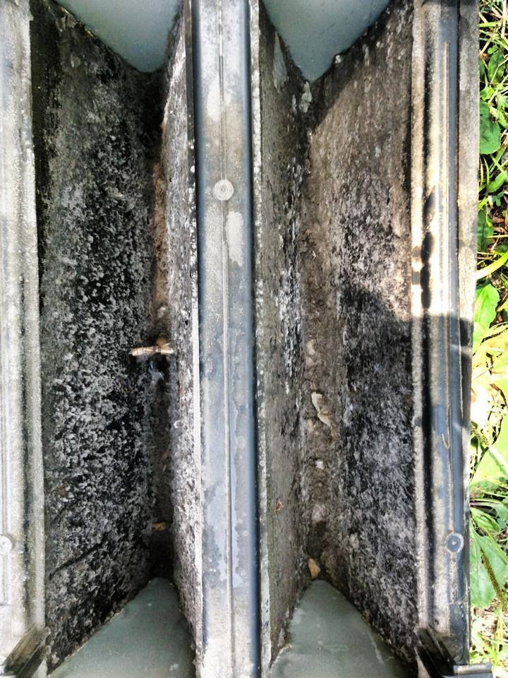 A close up of a dirty air filter sitting on the ground.