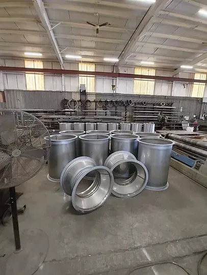 A bunch of metal pipes are sitting on the floor in a factory.
