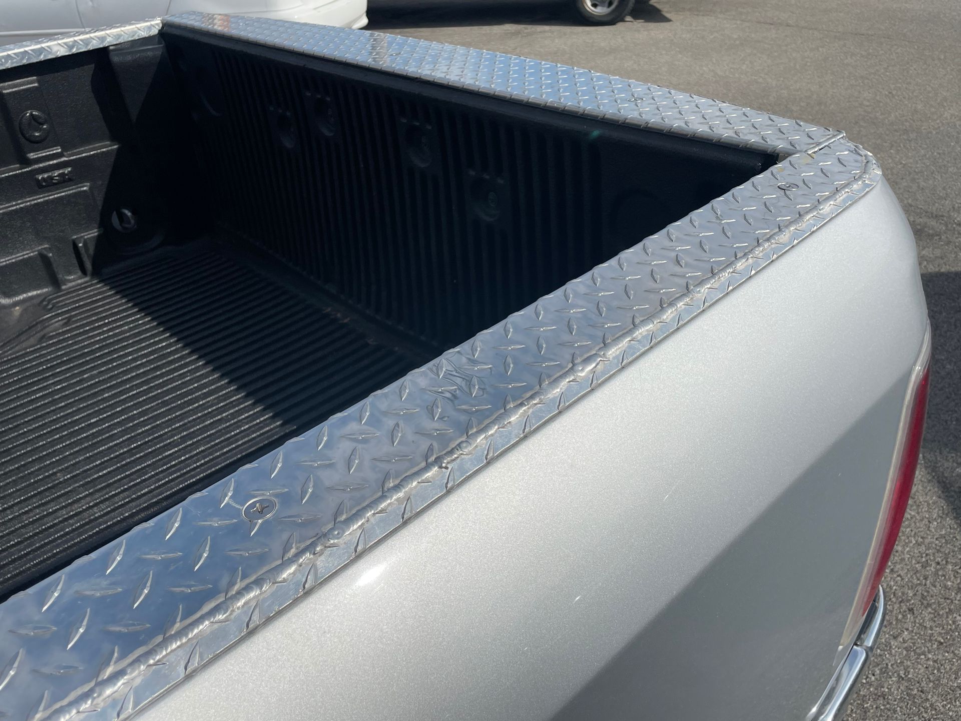 A silver truck with a diamond plate on the bed.