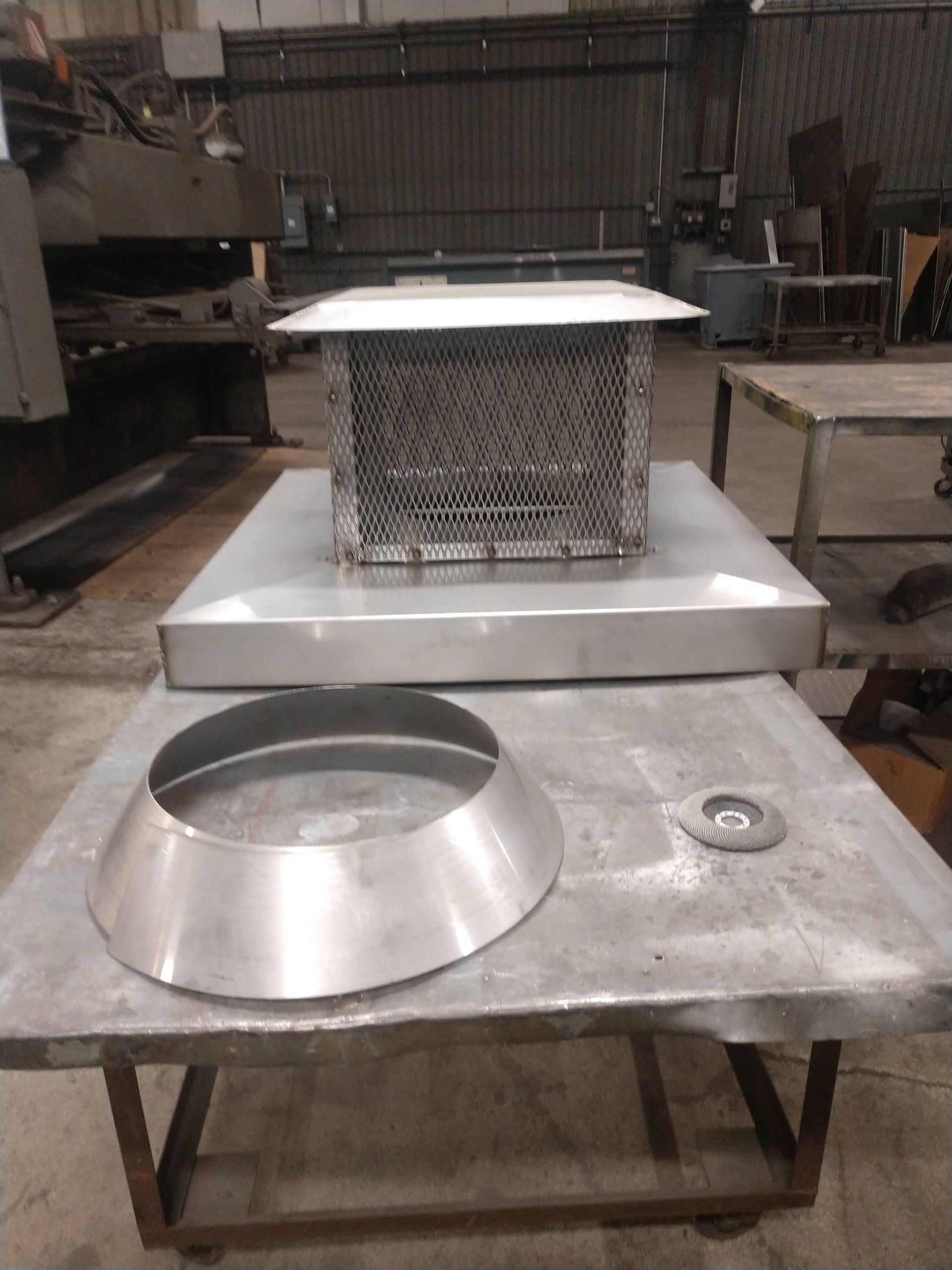 A stainless steel chimney sitting on top of a metal table.