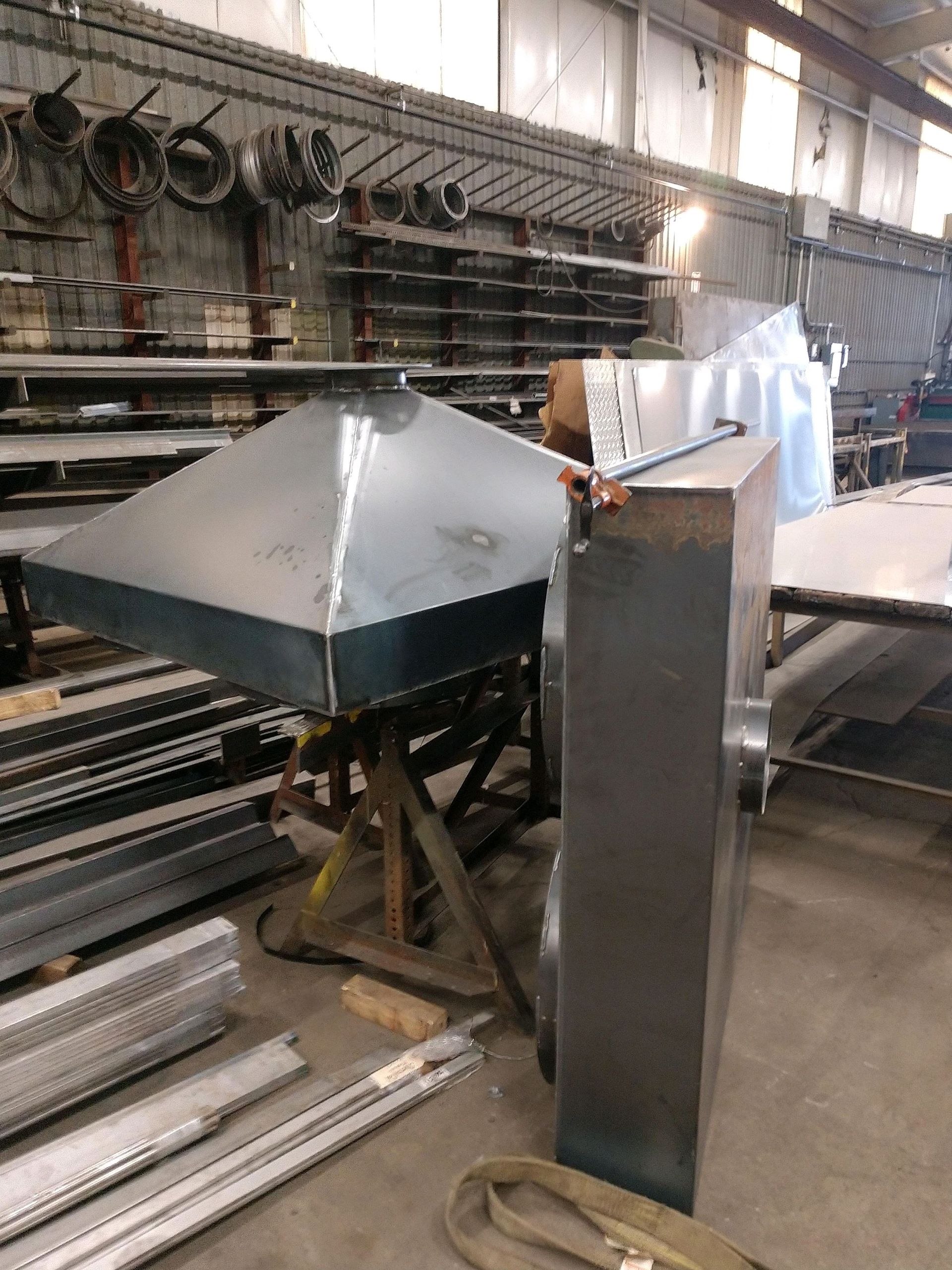 A warehouse filled with lots of metal pieces and a metal hood.