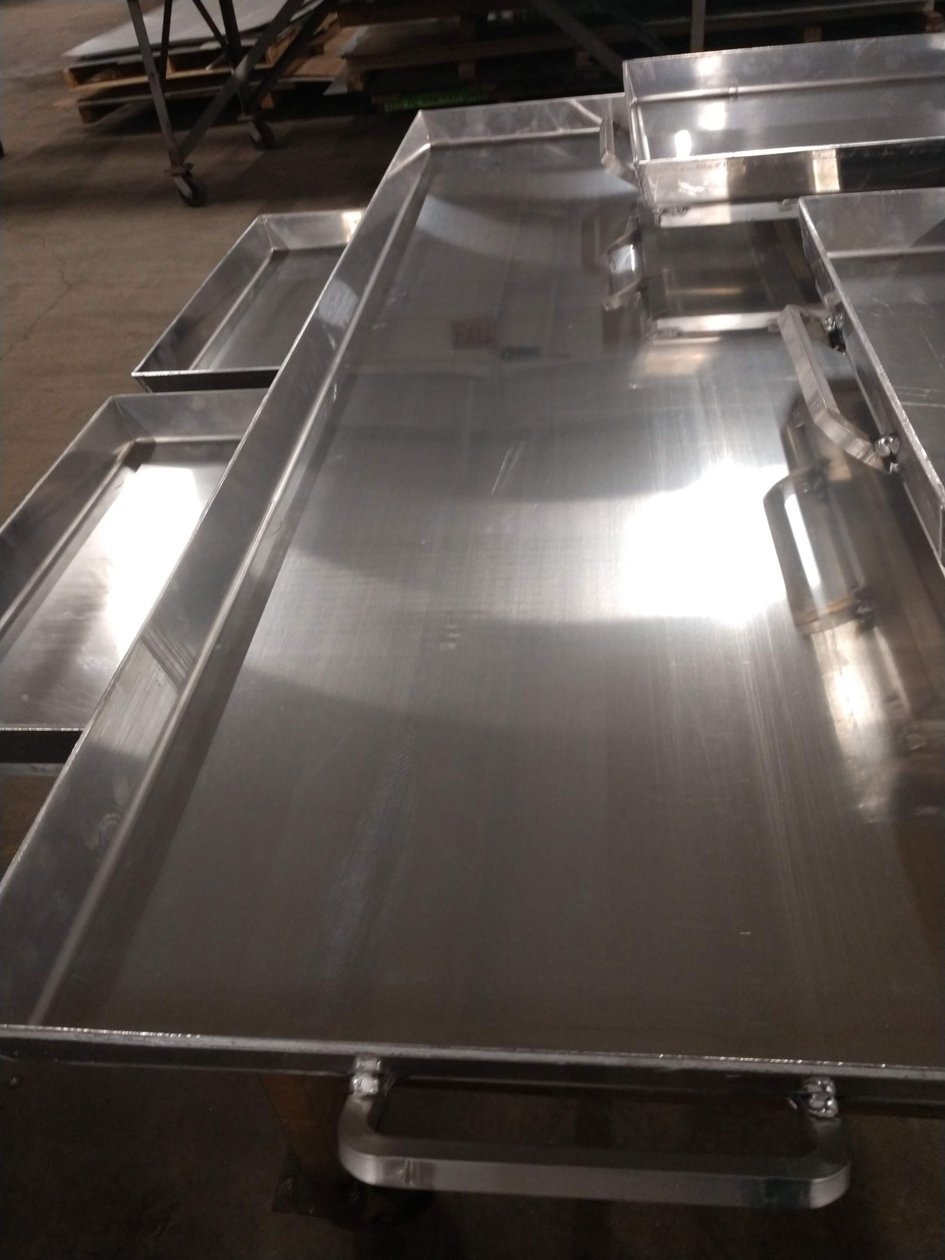 A bunch of stainless steel trays are sitting on top of each other on a table.