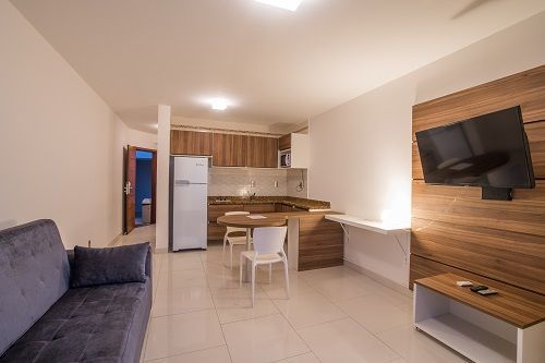 Un salón con sofá, televisión, mesa de comedor y sillas.