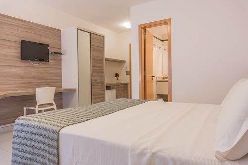 Una habitación de hotel con una cama grande y una televisión de pantalla plana.