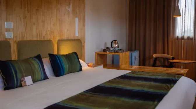 Una habitación de hotel con cama, escritorio, silla y ventana.