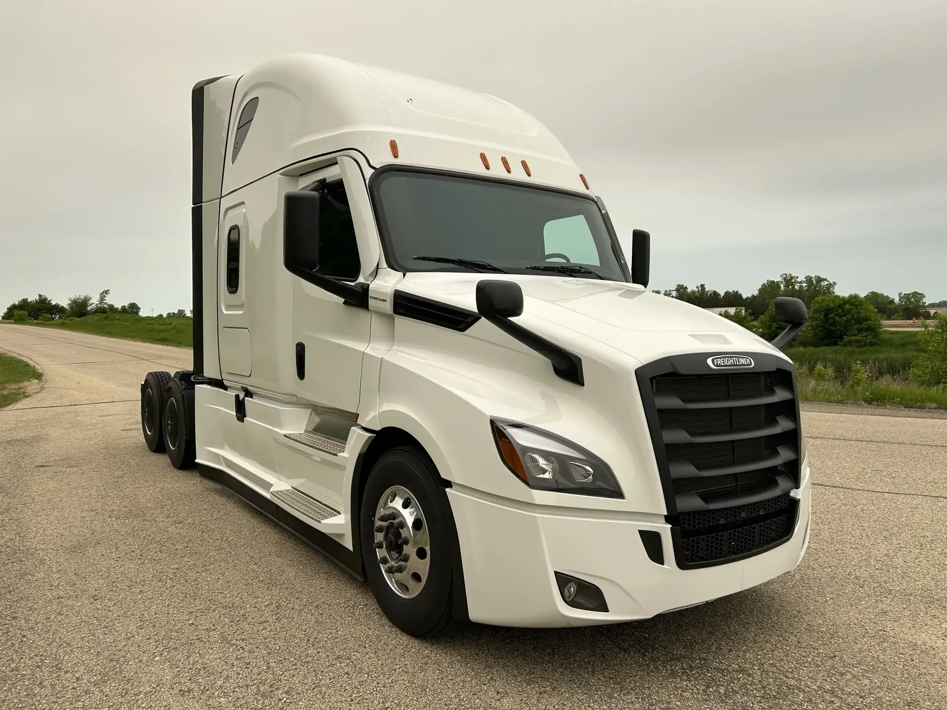 White semi-truck parked on a gravel road.