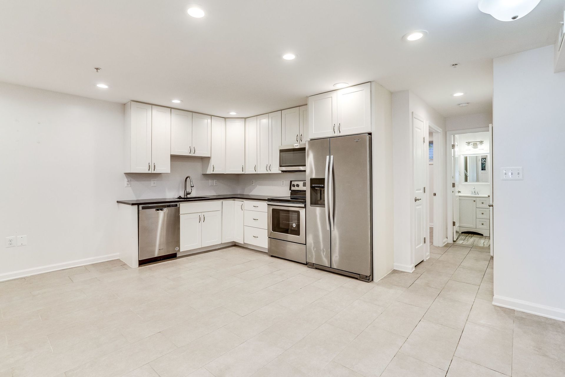 An empty kitchen with white cabinets and stainless steel appliances