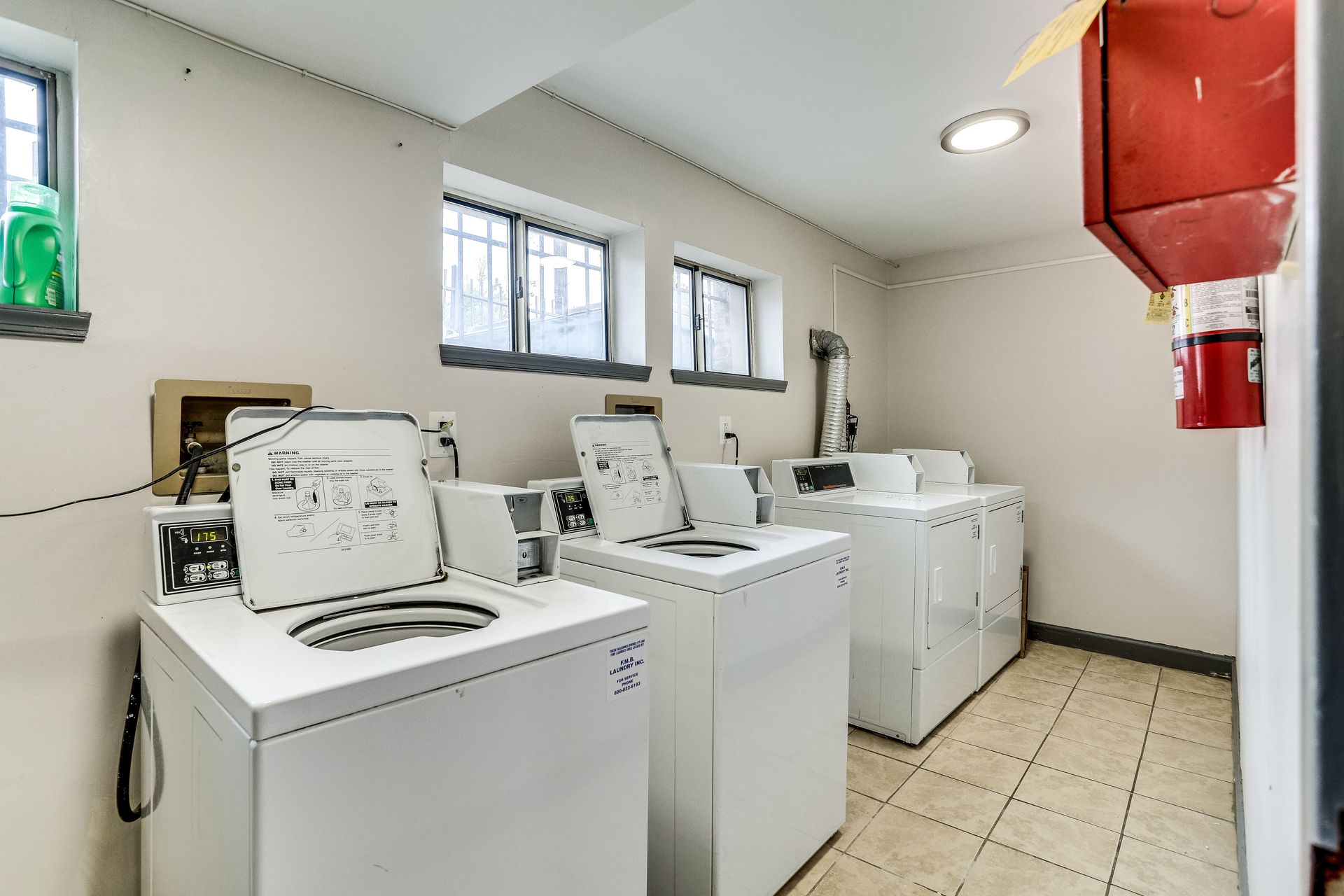 A laundry room with washers and dryers and a fire extinguisher.