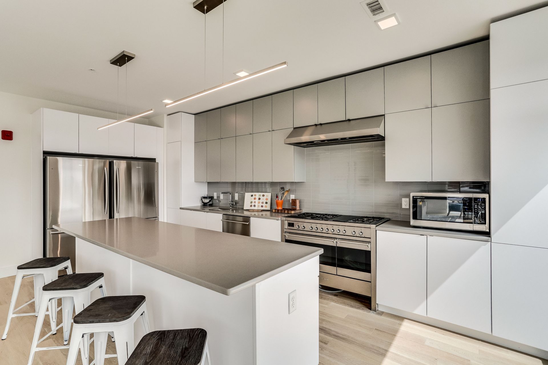 A kitchen with white cabinets , stainless steel appliances , and a large island.