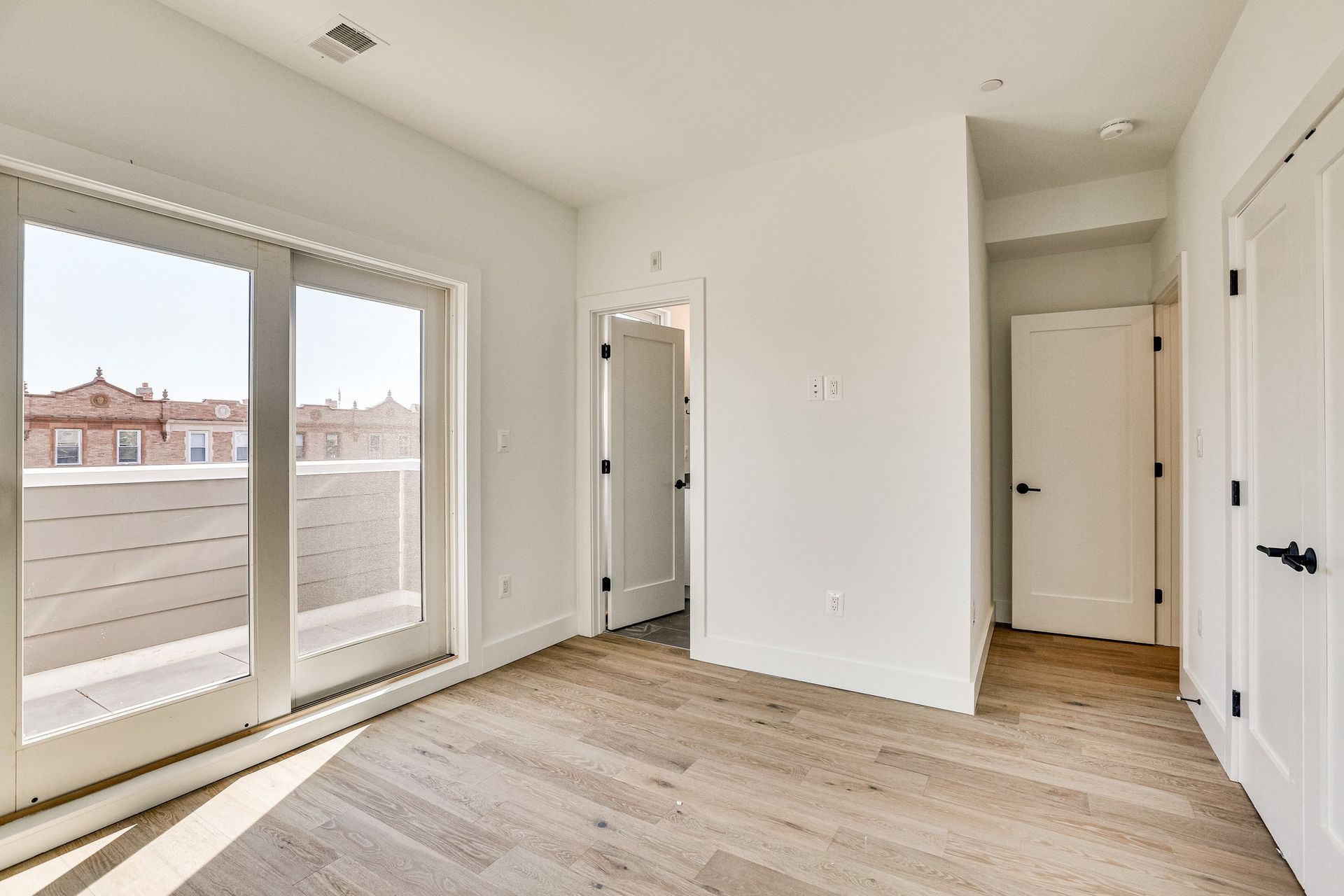 An empty room with hardwood floors and sliding glass doors.