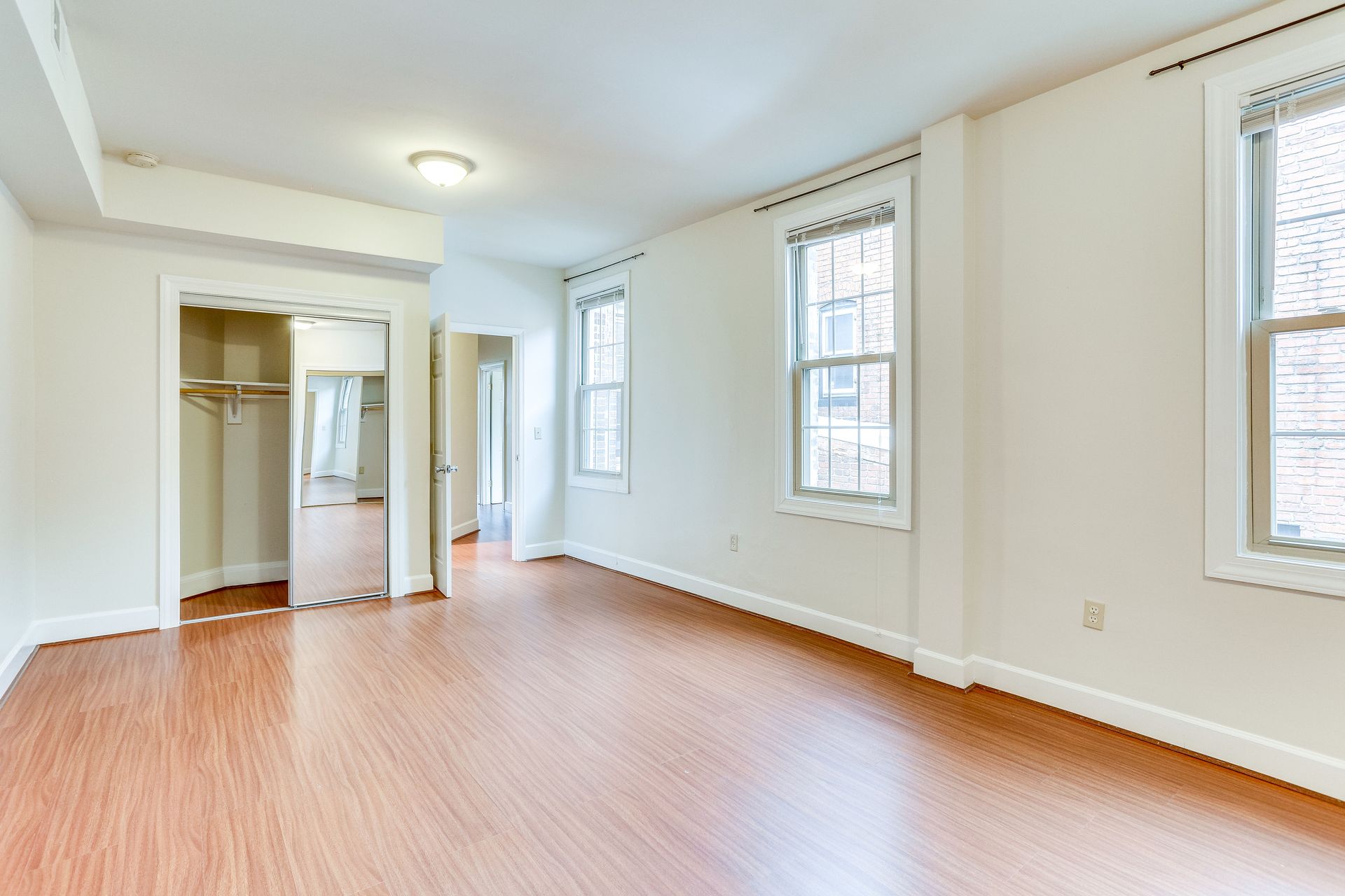 A large empty room with hardwood floors and white walls.
