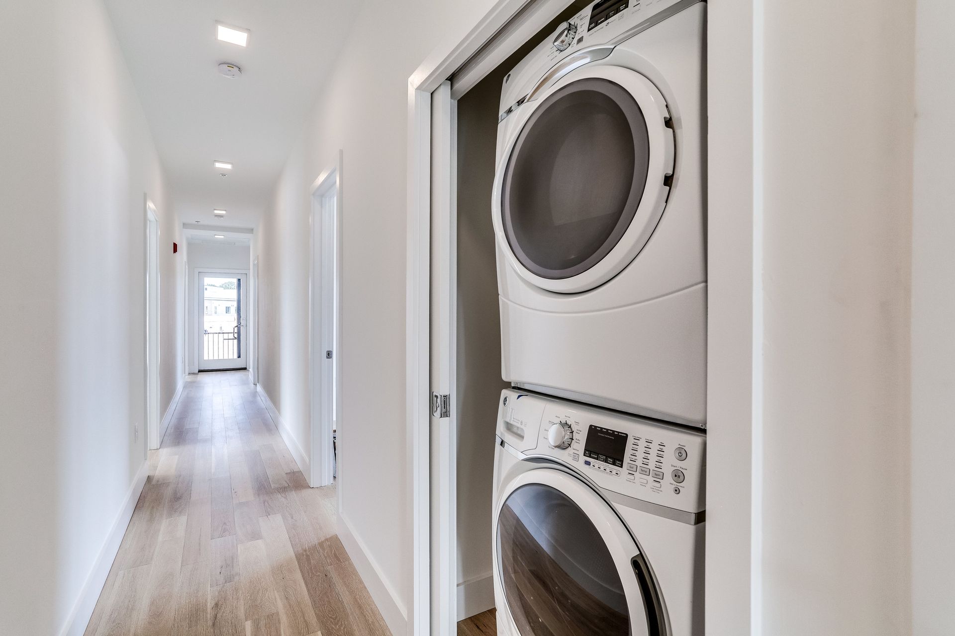 A washer and dryer are stacked on top of each other in a hallway.