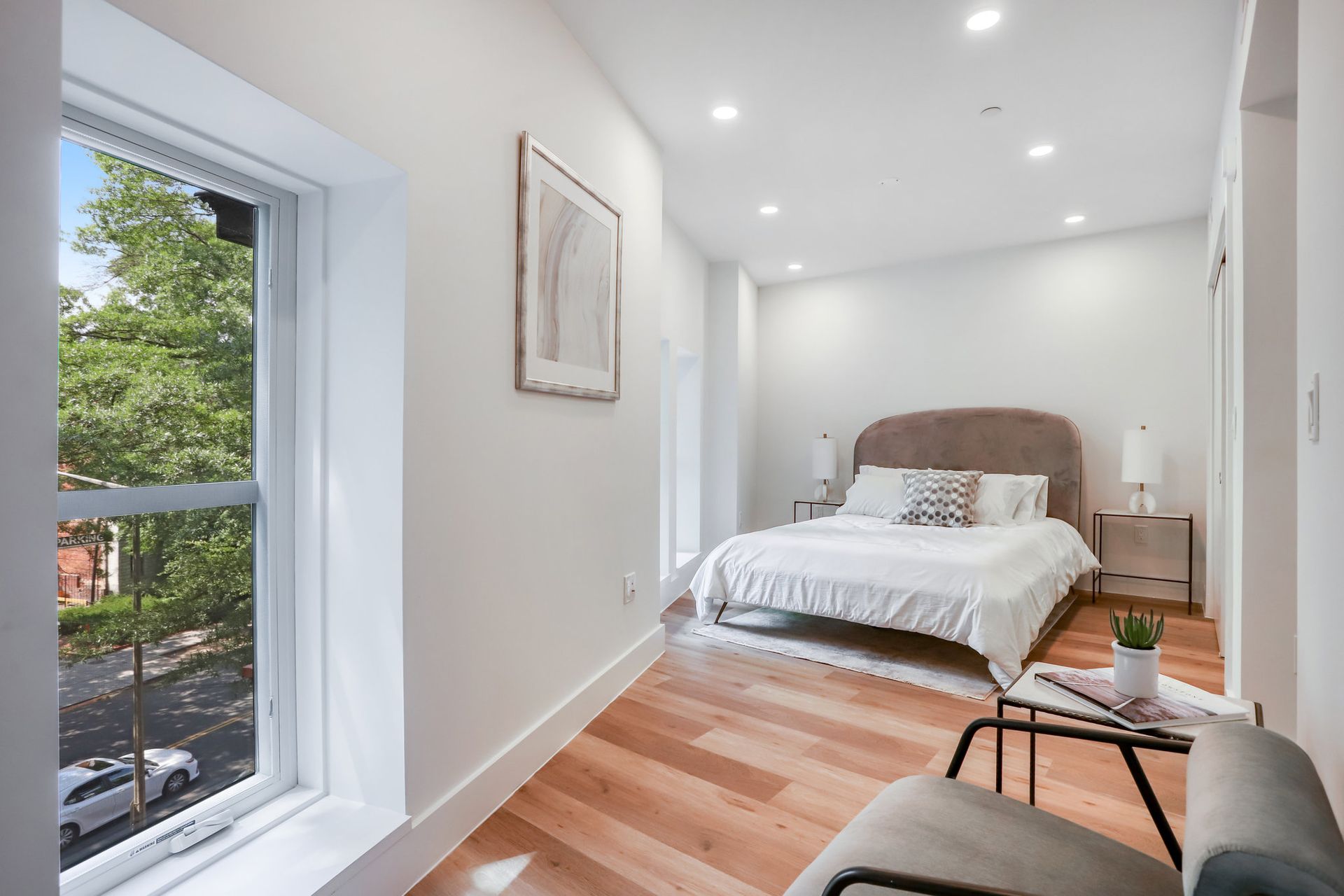 A bedroom with a bed , chair , table and window.