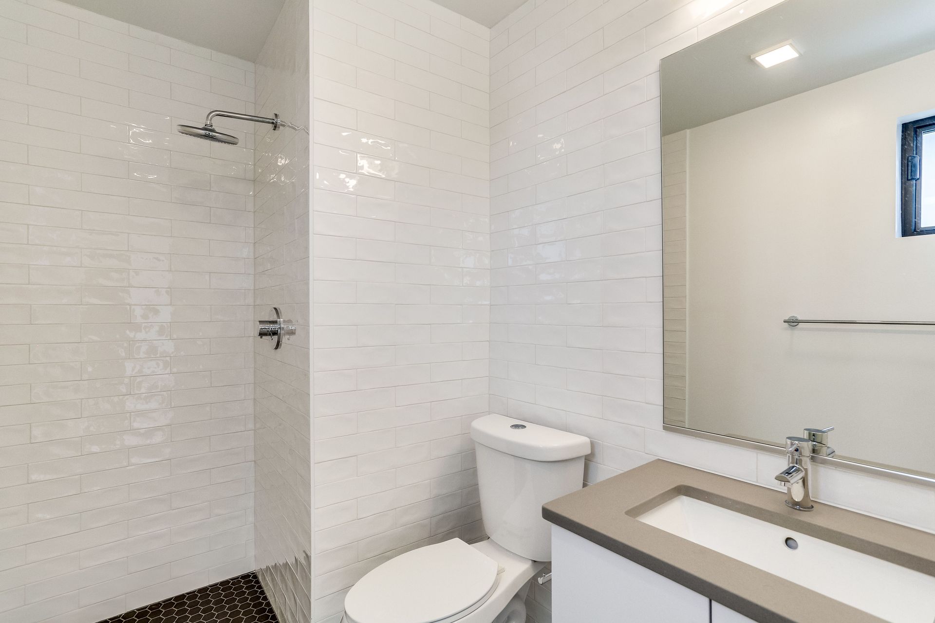 A bathroom with a toilet , sink and shower.