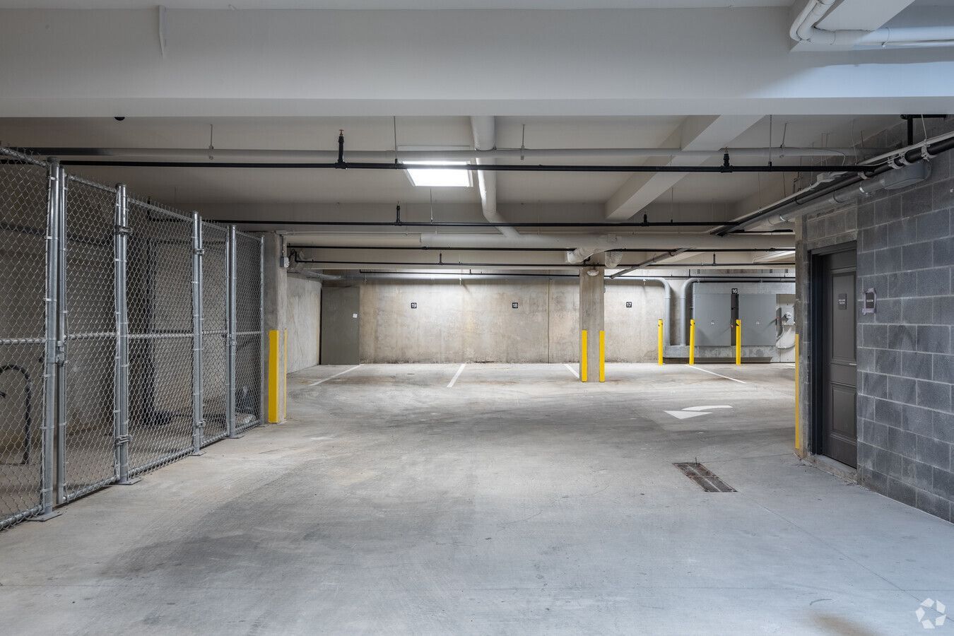 An empty parking garage with a chain link fence and a door.