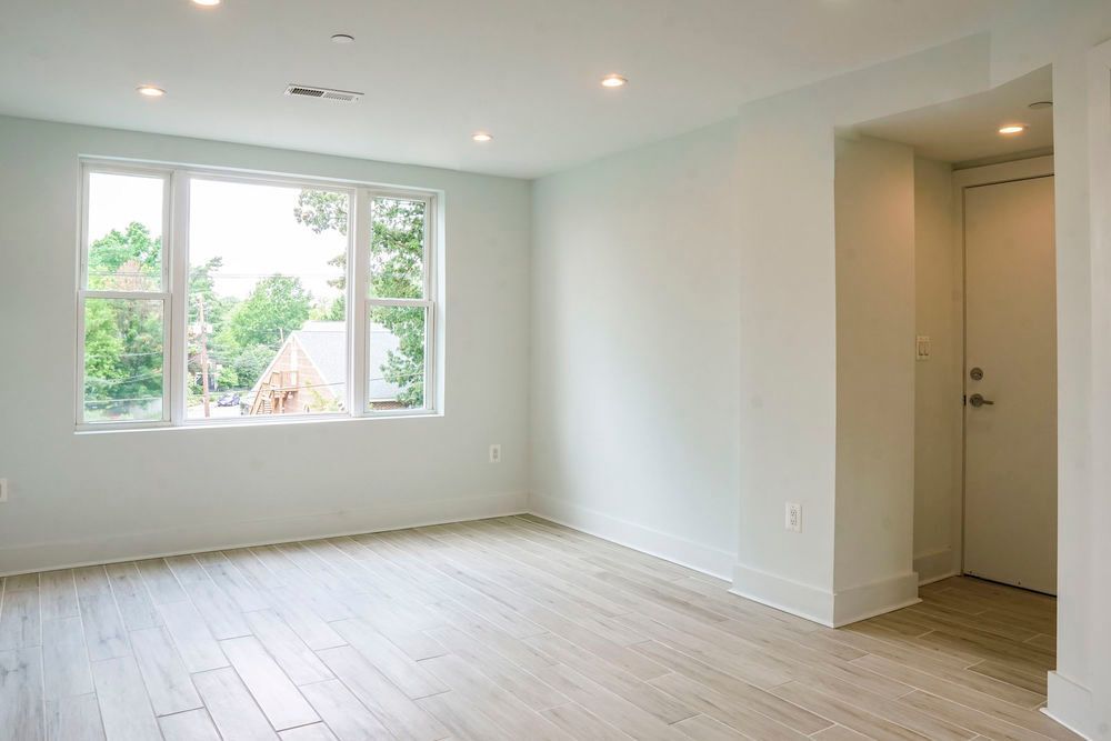 An empty room with hardwood floors and a window.