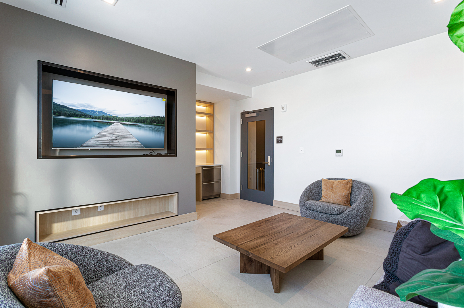 A living room with two chairs , a coffee table , and a flat screen tv.