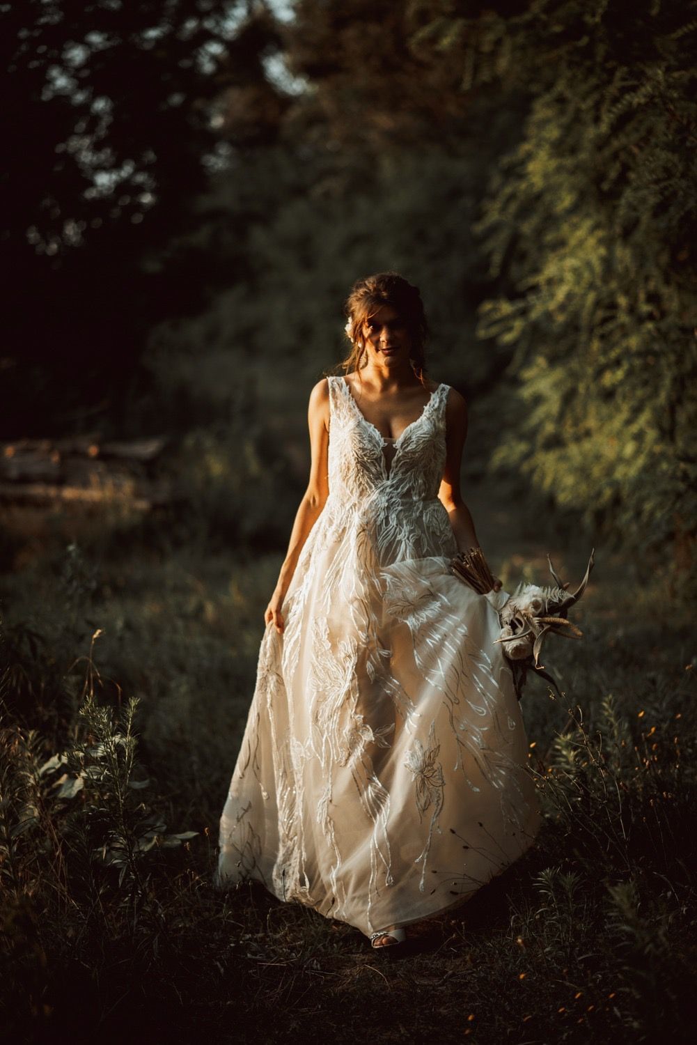 Sposa in abito bianco che cammina in una zona boscosa, tenendo in mano il bouquet.
