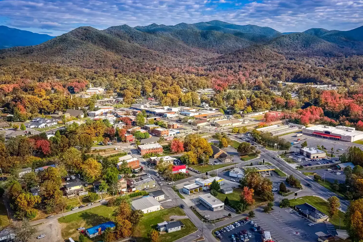 Aerial view of a small town nestled among colorful autumn trees and mountain hills