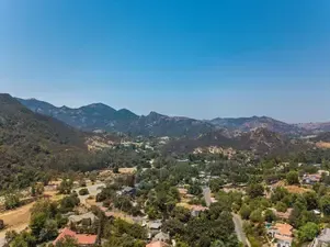Mountain landscape with green hills, scattered homes, and a clear blue sky