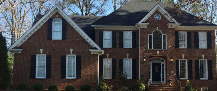Brick house with black shutters, a dark roof, and arched windows.