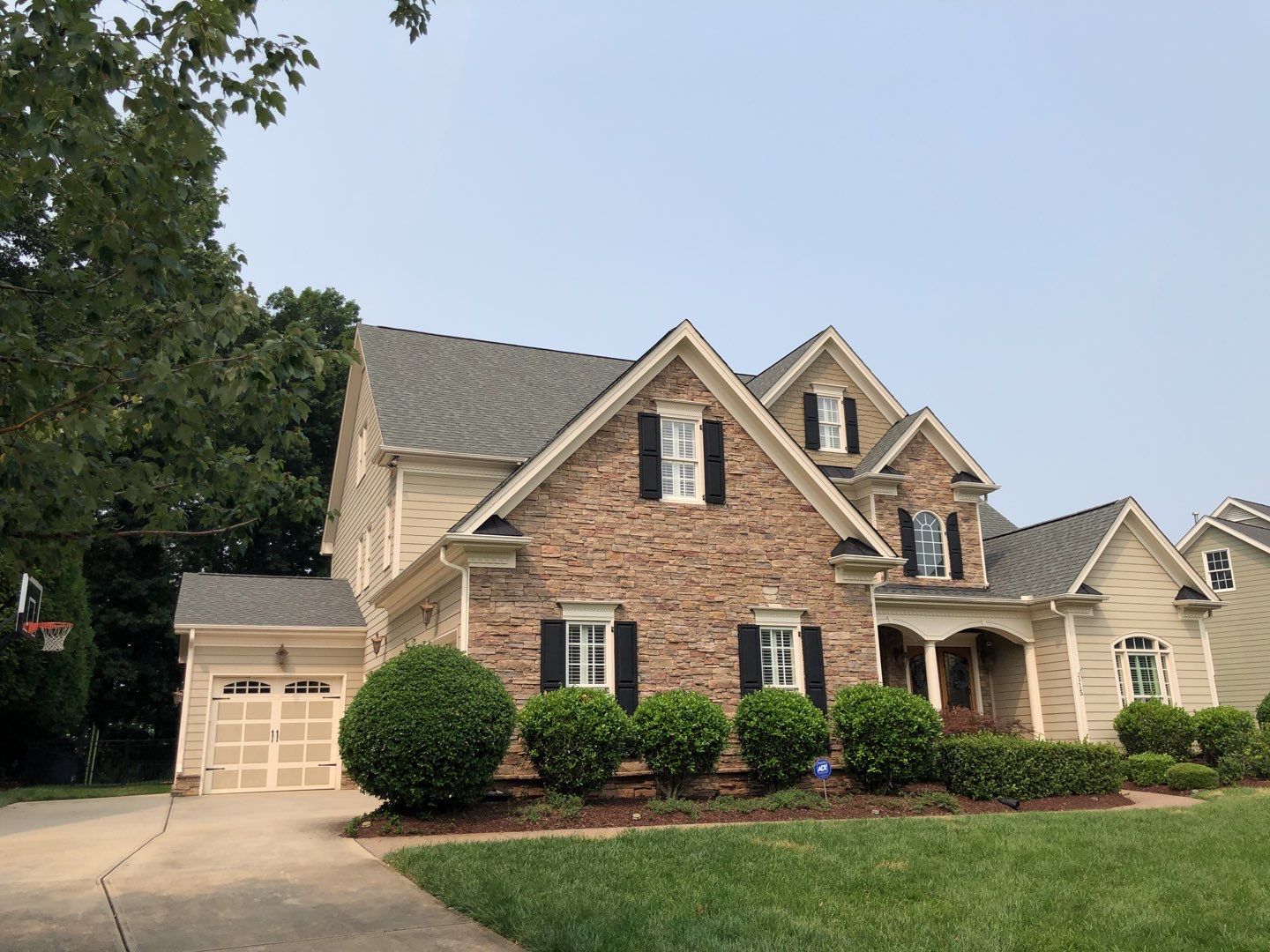 Two-story house with brick facade, shutters, and well-manicured lawn.