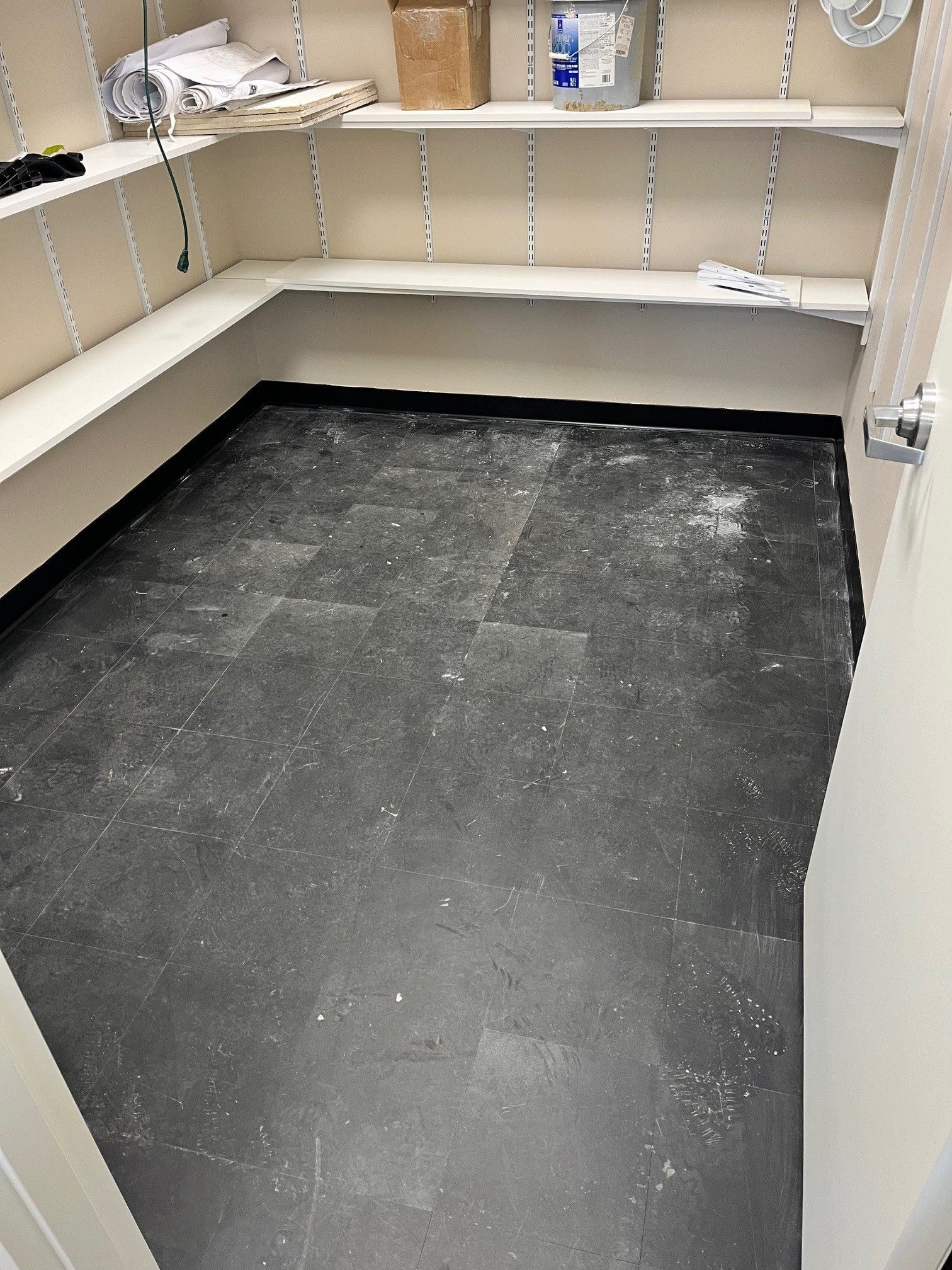 A pantry with empty shelves and a dark floor.