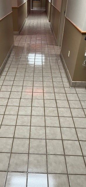 A long hallway with tile floors and brown walls.