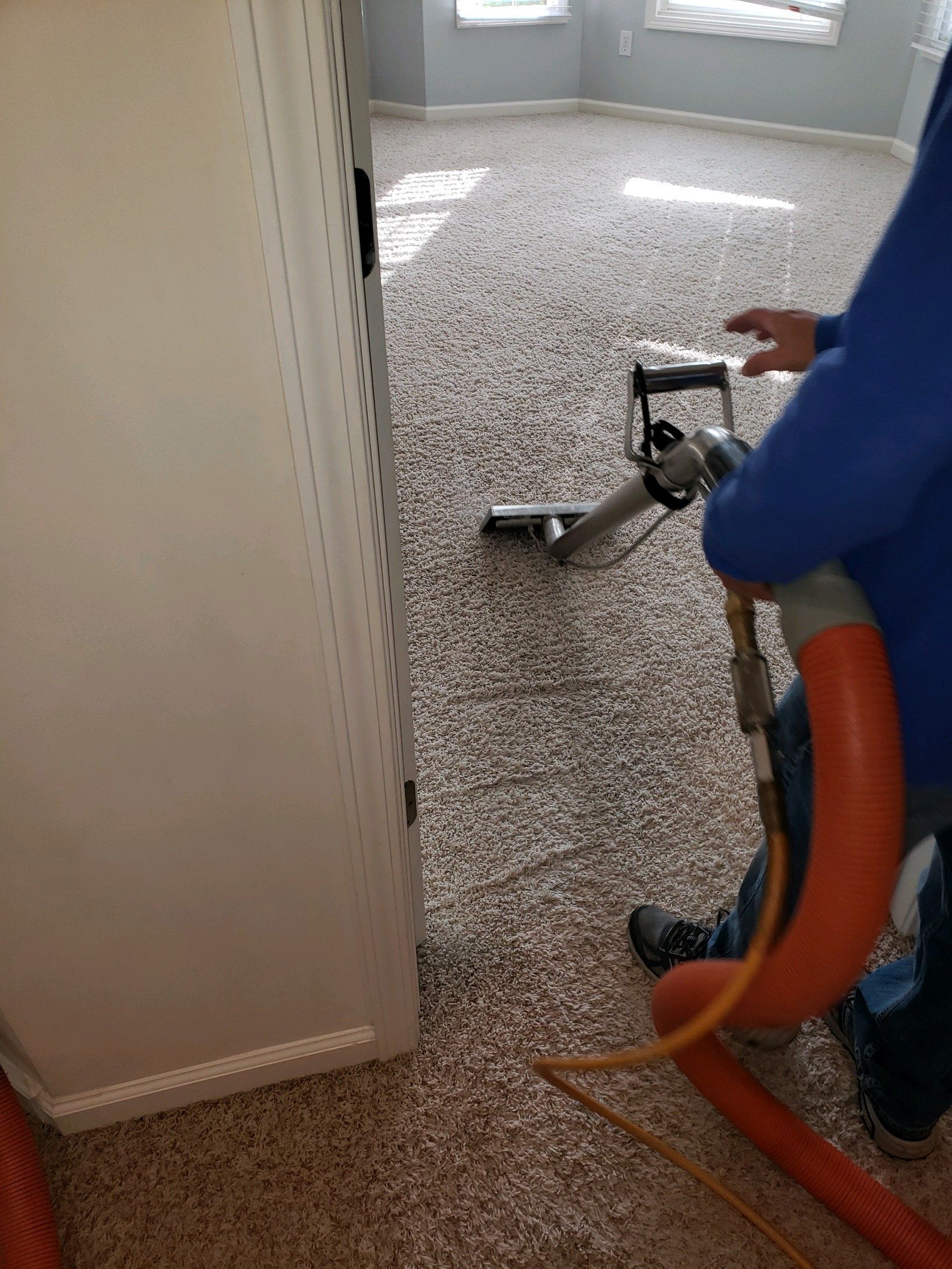 A man vacuuming a living room carpet, showcasing a tidy home and effective carpet cleaning.