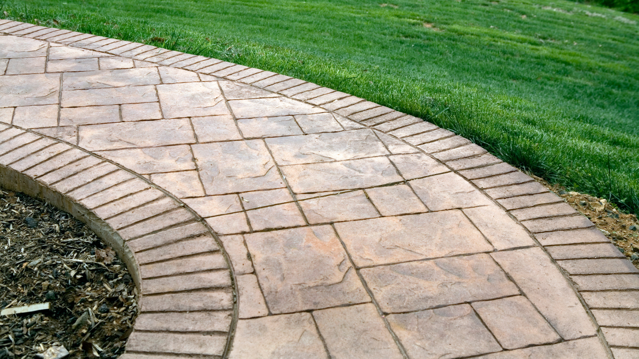 A stamped concrete walkway with green grass surrounding it