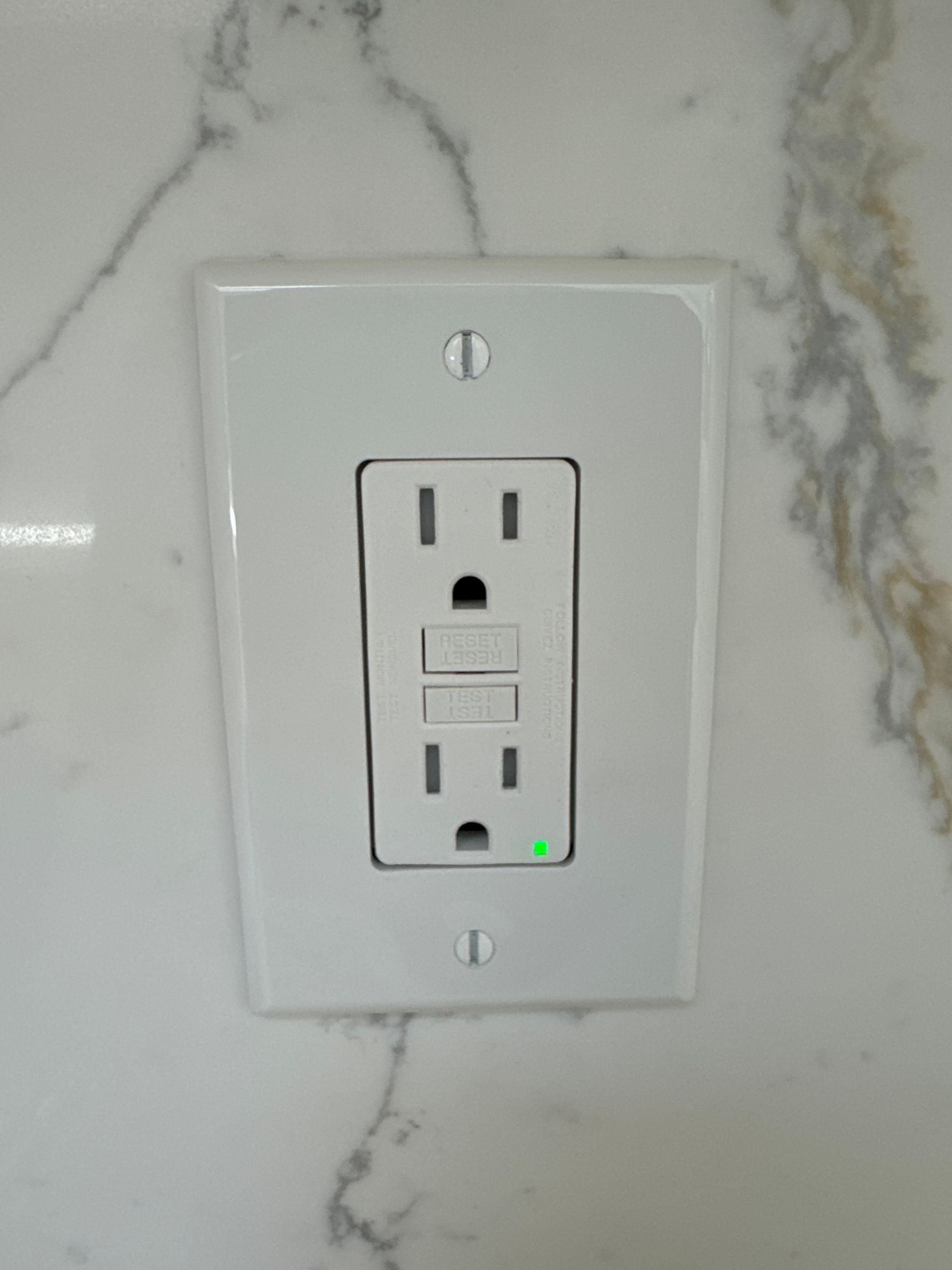 Electrical outlets and switch with exposed wiring set in a gray wall.
