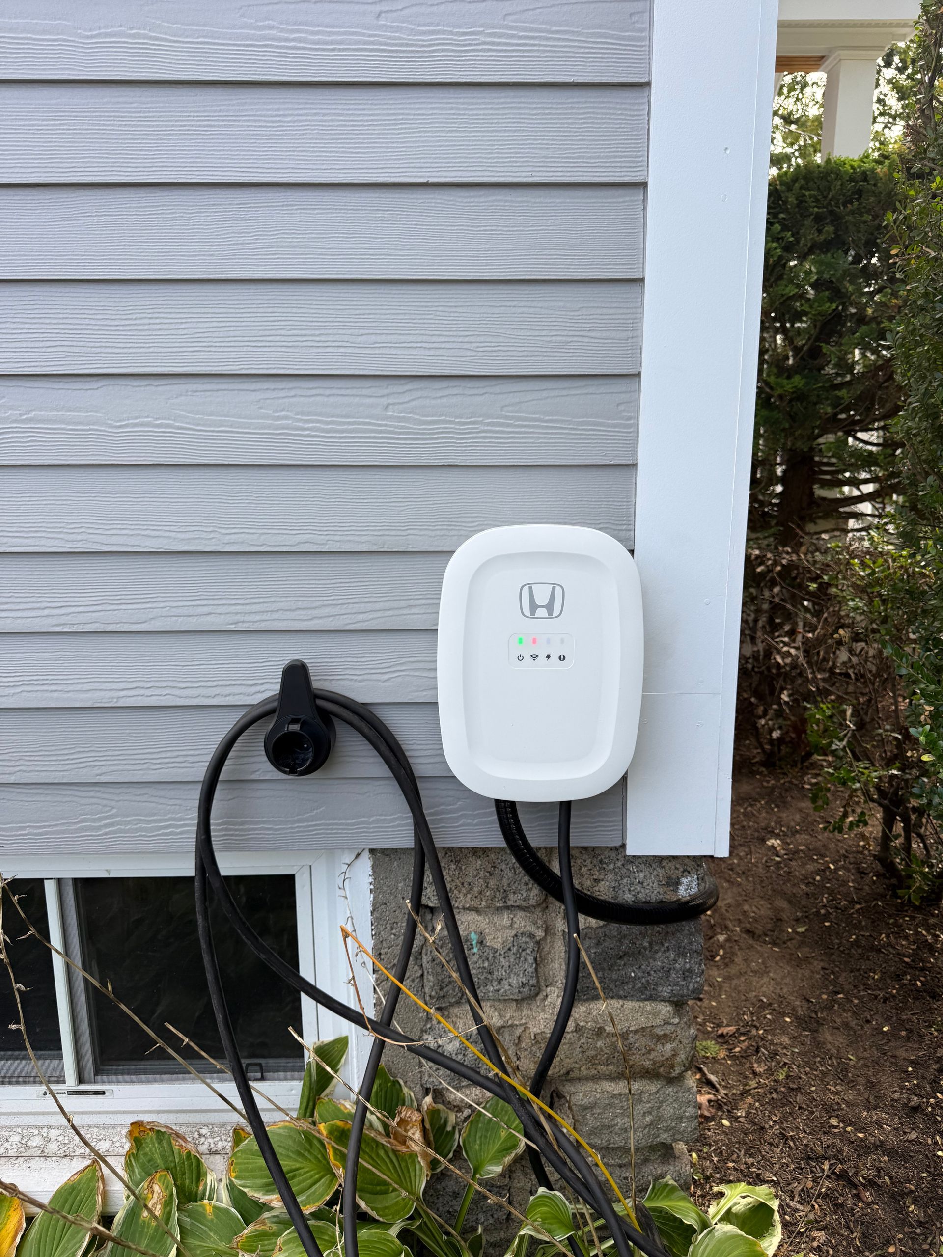 Hand testing an electrical outlet with red and black probes. Wires are visible, wall is white.