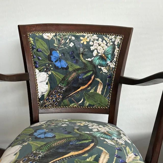 Stoel met donker houten frame en bekleding met pauwen- en vlindermotief.