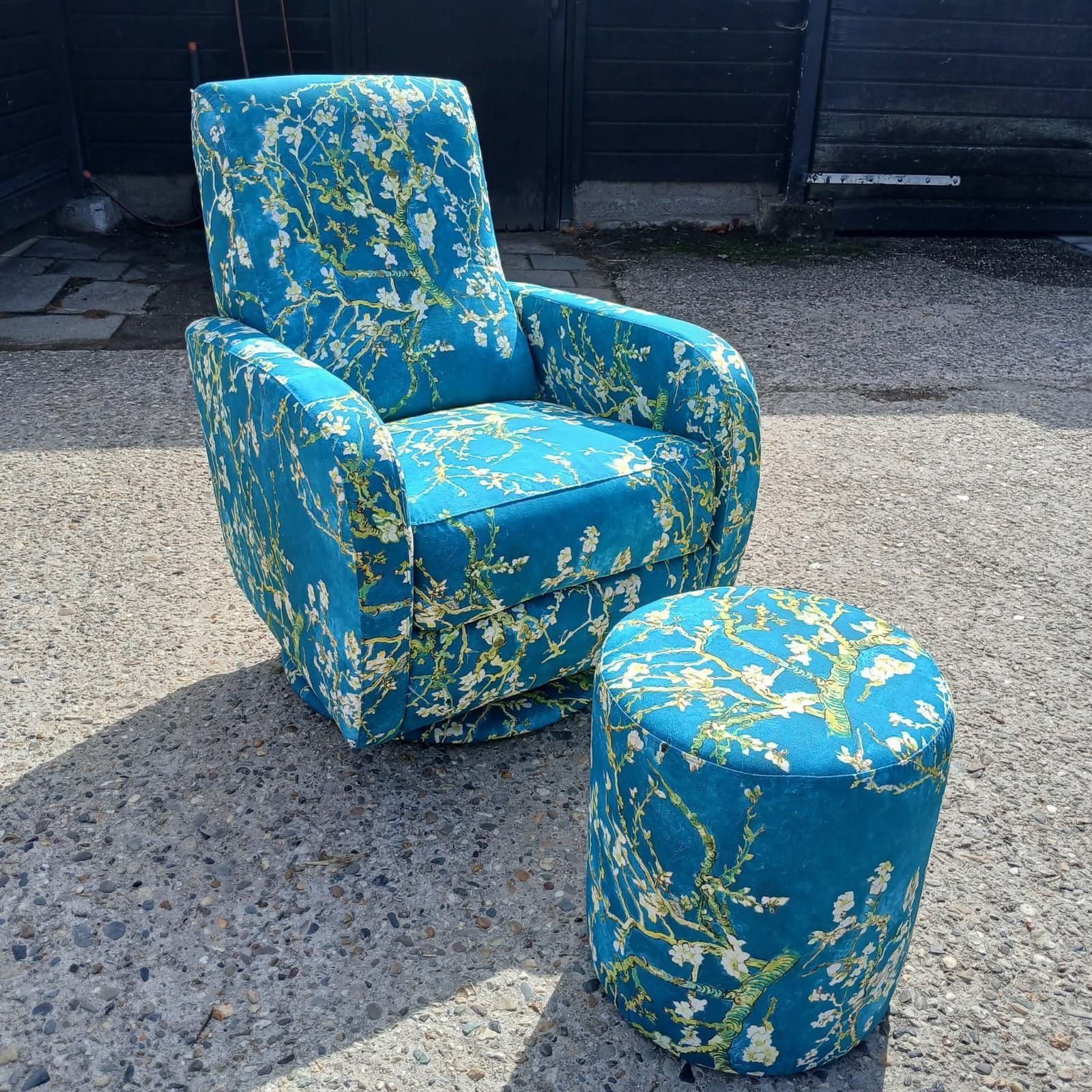 Turquoise armchair and ottoman set with floral print on concrete.