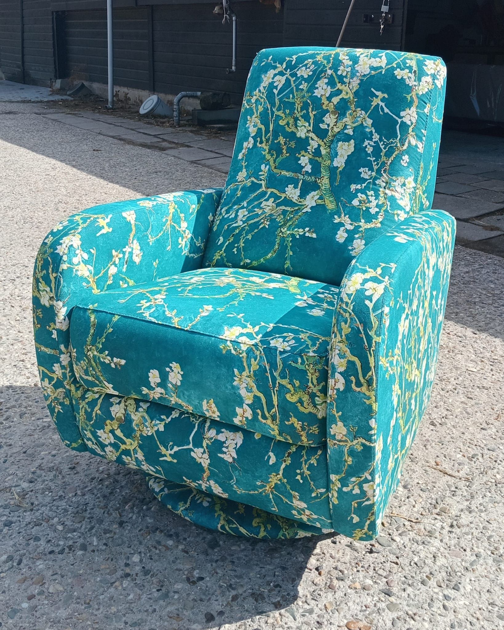 Draaifauteuil met blauwgroen patroon op een betegelde ondergrond, buiten.