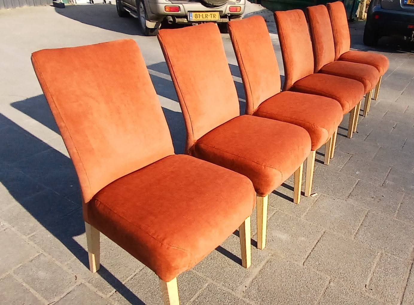 Zes oranje gestoffeerde eetkamerstoelen stonden buiten op een zonnige dag.