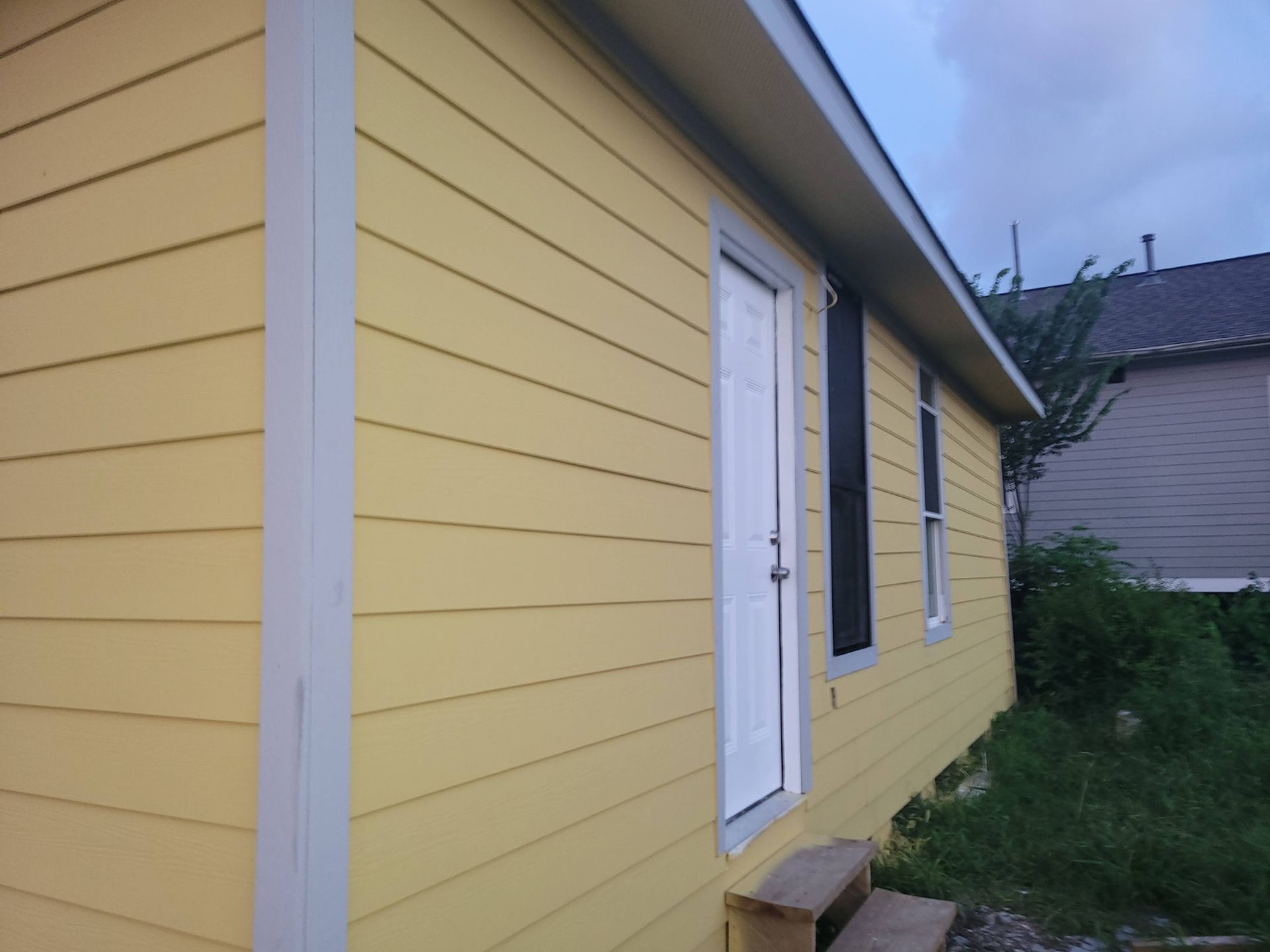 Yellow house with white door, black shutters, and light blue trim.