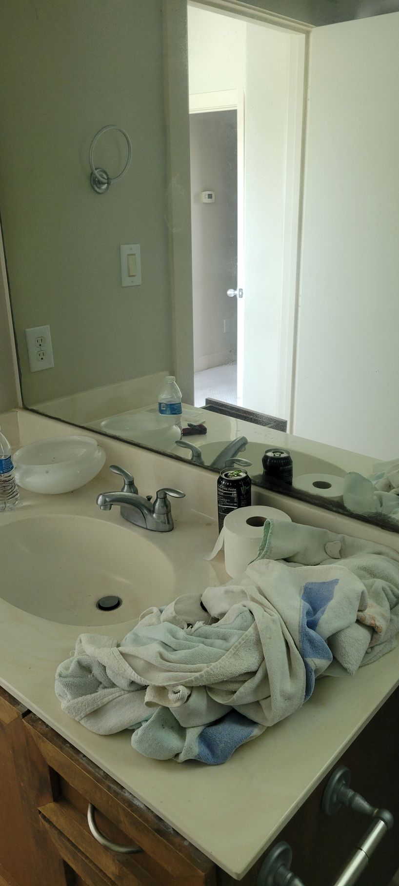 Bathroom sink with towels, mirror, and open doorway.