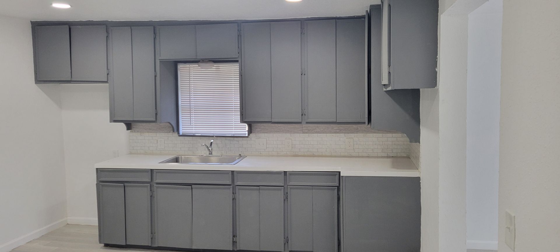Grey kitchen with cabinets, countertops, and a window.