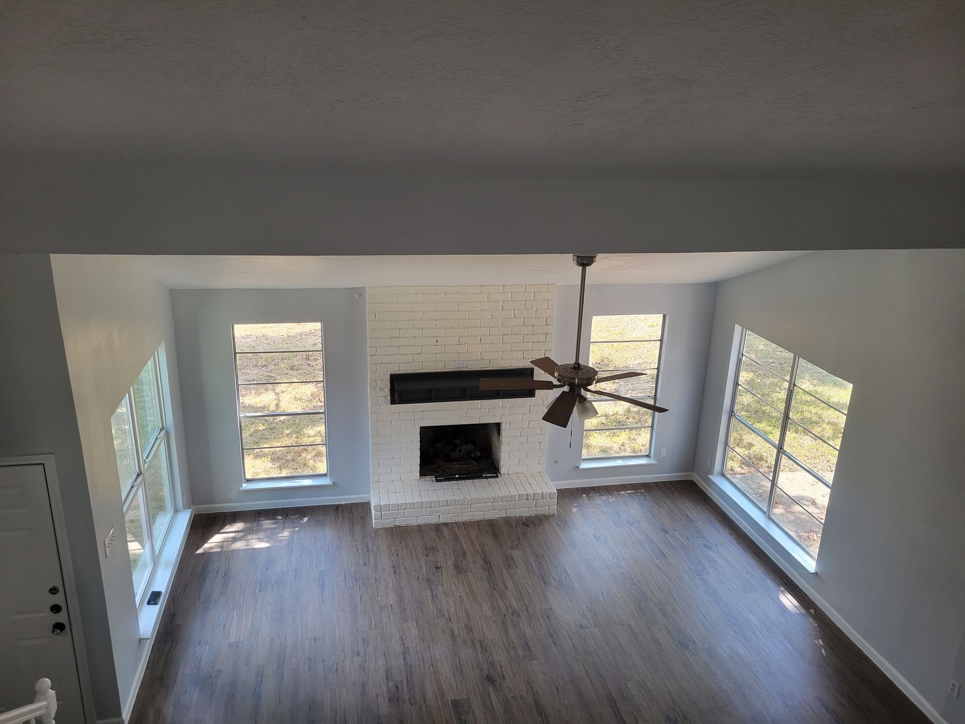 Overhead view of a living room with a brick fireplace, windows, and a ceiling fan.