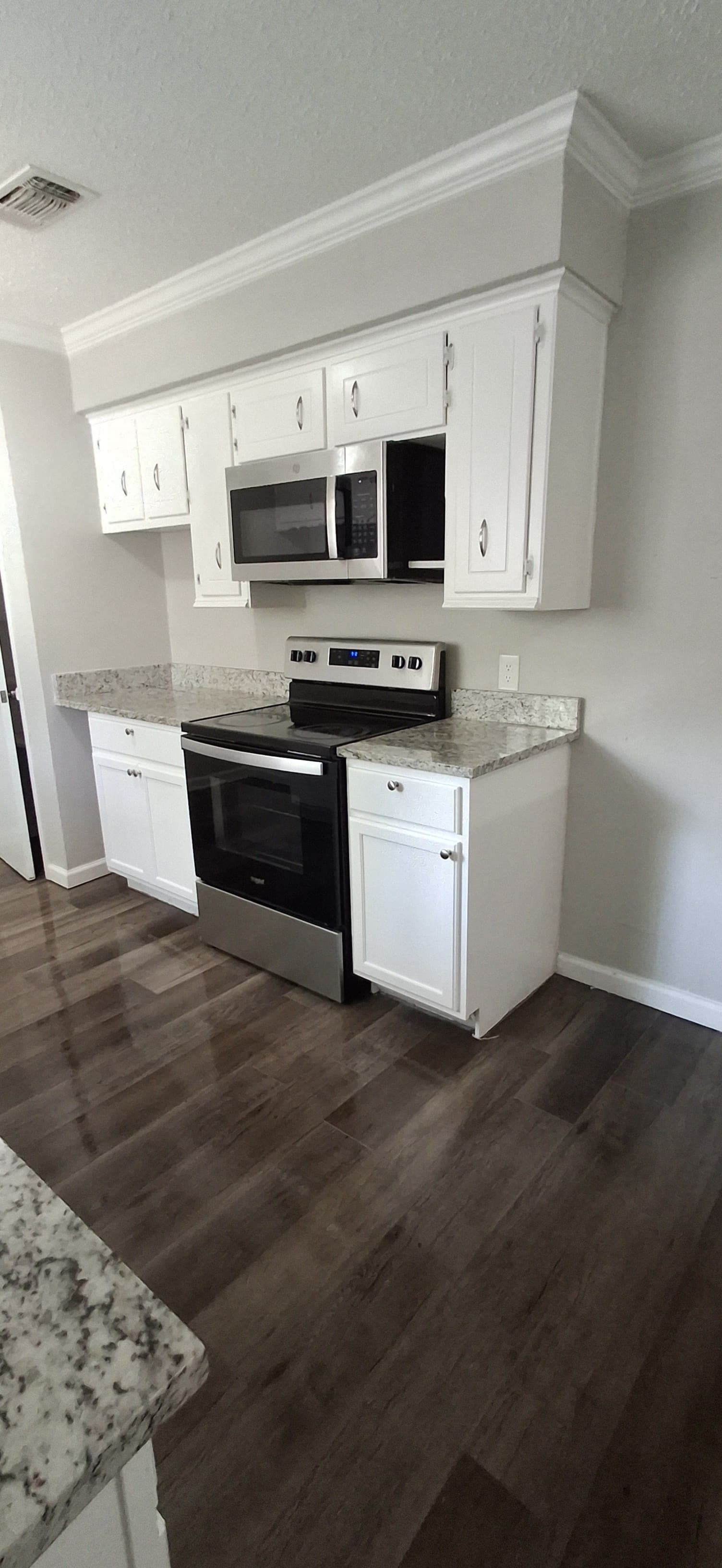 Kitchen with white cabinets, stainless steel appliances, and dark wood floors.