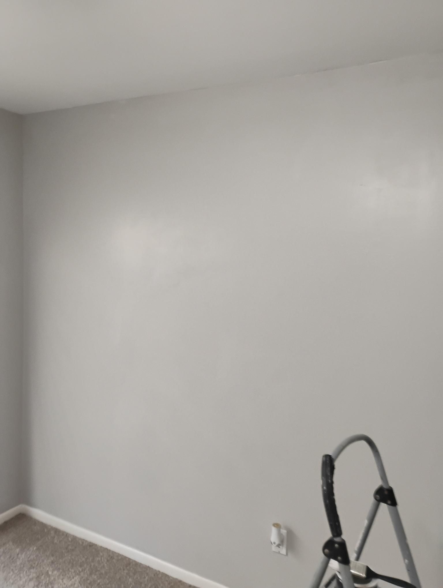 Gray painted wall with a step ladder leaning against it. A white electrical outlet is visible.