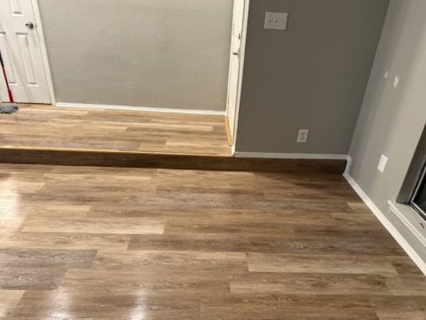 Laminate wood flooring in a room with a raised platform, gray walls, and white trim.