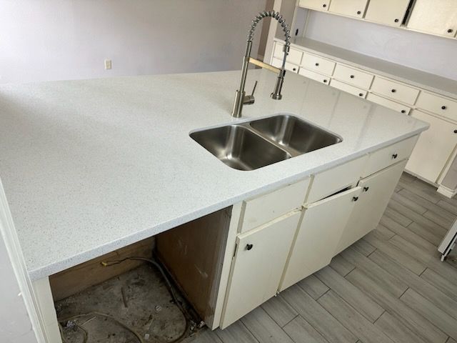 White kitchen island with a double sink and a faucet. Cabinets below, unfinished side.