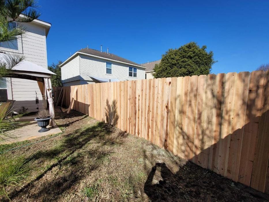 Wooden fence in a backyard, with a house and clear blue sky in the background.