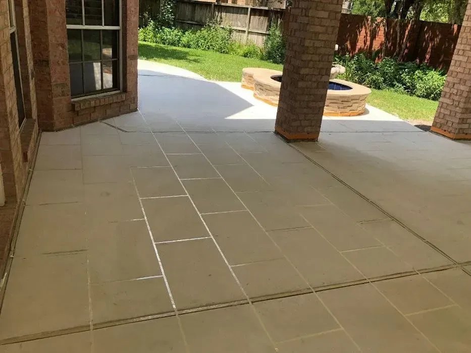 Patio with beige tiled floor, brick columns, and a grassy backyard with a fire pit.
