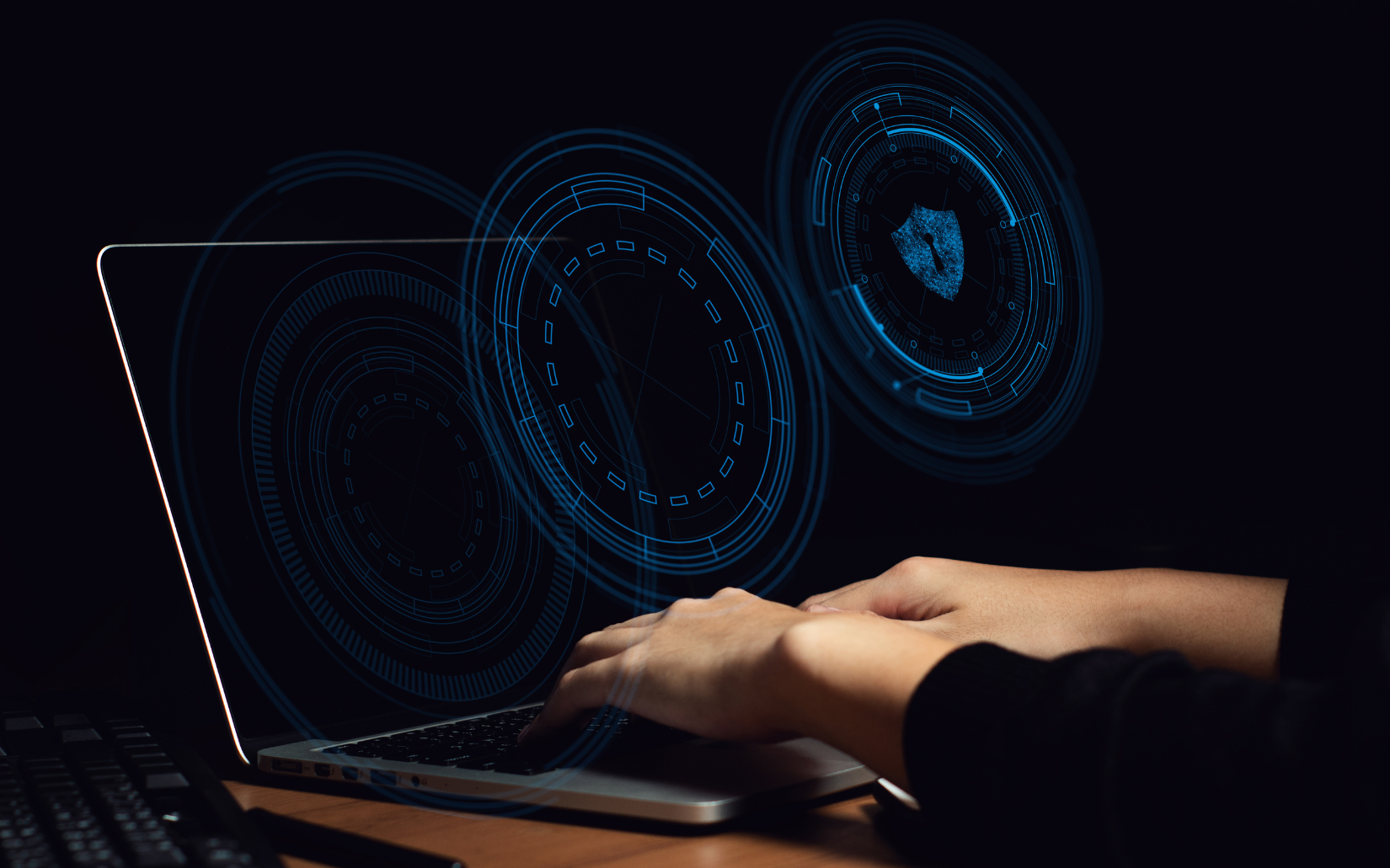 Hands typing on a laptop with glowing blue circular digital overlays, symbolizing data security or hacking.