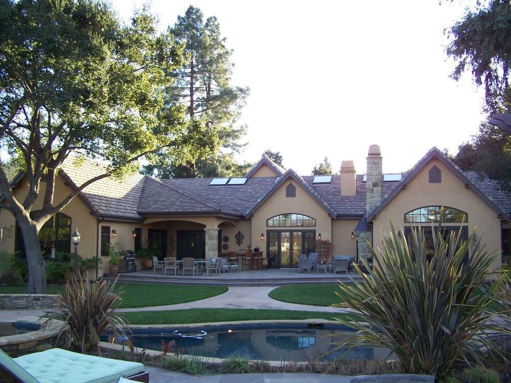 Corner of a stone building with brown trim, gutter, and a lit lantern. Archway with lights on the left.