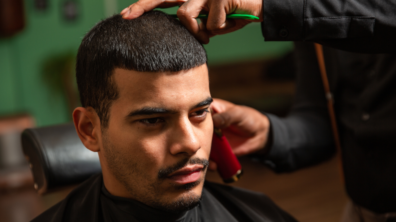 Man getting a haircut in a barbershop; barber using clippers.